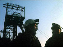 Pithead and miners silhouetted against a blue sky
