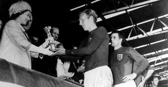 Geoff Hurst watches as England captain Bobby Moore is presented with the World Cup