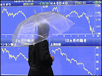 Một người đi qua bảng chỉ số chứng khoán ở Tokyo