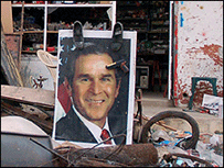Pôster de Bush em Khiam, no sul do Líbano, enfeitado com sapatos e armas de brinquedo  Foto: Martin Asser, 2006