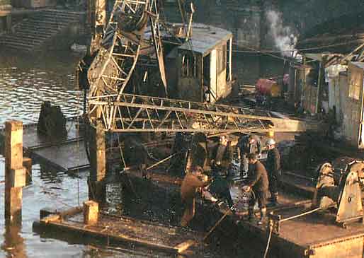 Close-up view of workers in Peter Bannister's photo of cranes, beside Queen Elizabeth II Bridge in Belfast. (1966)