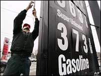 Funcionário de posto de gasolina trocando preços em cartaz