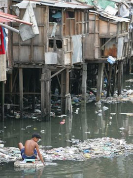 Boy collects water in a slum near Manilla