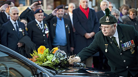 A veteran soldier places a bunch of flowers on the bonnet of Ranger Aaron McCormick's hearse.