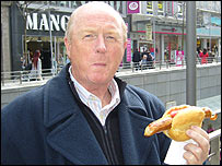 BBC Radio Manchester commentator Fred Eyre samples a bratwurst in Hamburg