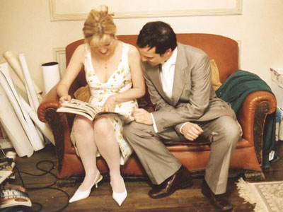 Alice and Andrew sitting on the sofa on set