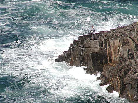 A fisherman fishing off the rough coast of Cornwall