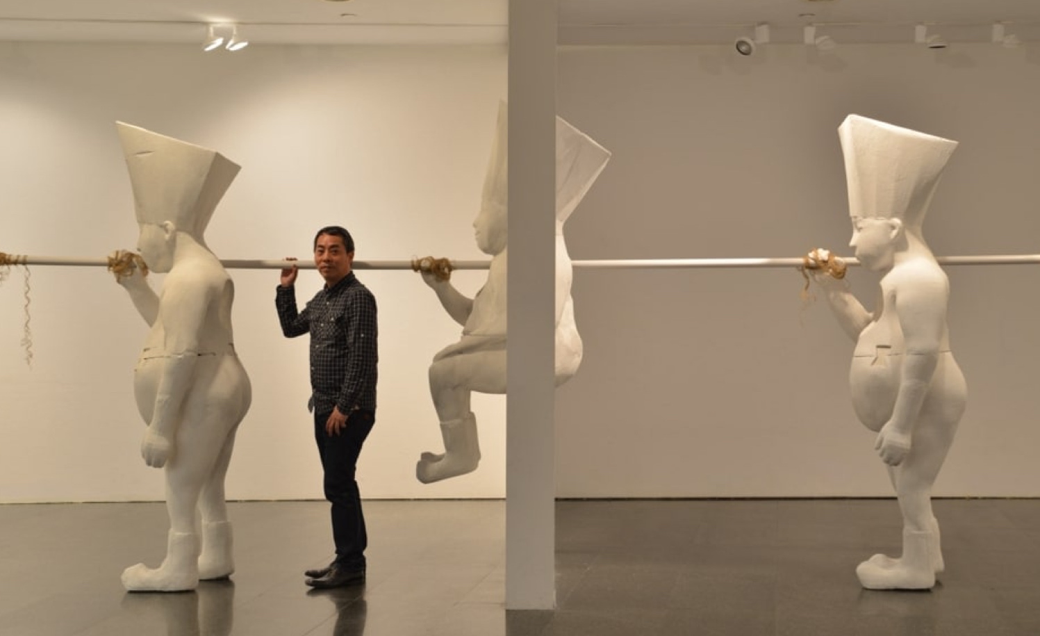 Artist James Wong standing in a gallery in front of his art installation.