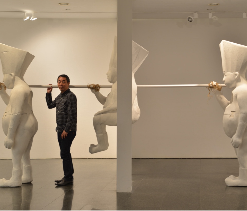 Artist James Wong standing in a gallery in front of his art installation.