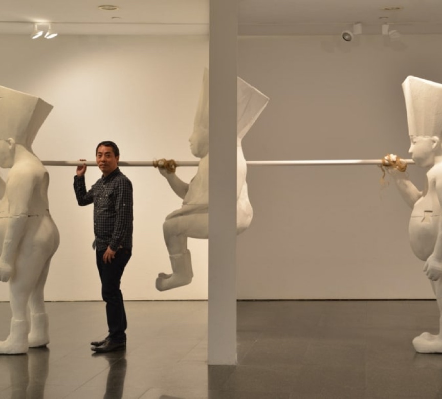 Artist James Wong standing in a gallery in front of his art installation.
