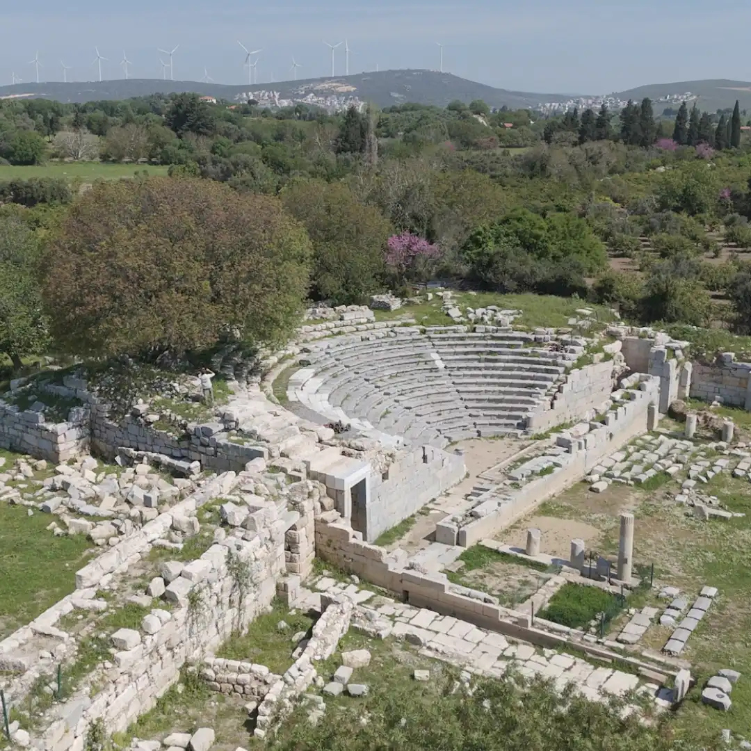 Aerial view of an ancient stone amphitheatre surrounded by ruins and countryside.