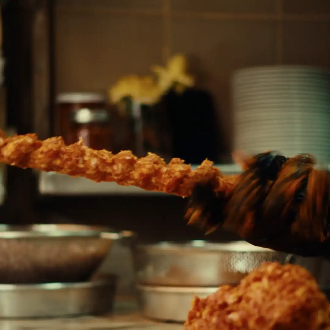 Crispy skewered kebab being grilled in a commercial kitchen.