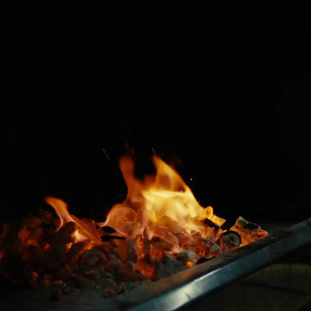Close-up of golden flames rising from a charcoal grill.